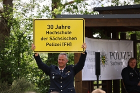 Foto: Erster Polizeihauptkommissar Thomas Knaup präsentiert den Anlass des Festaktes auf e nem nachempfundenen Verkehrsschild.
