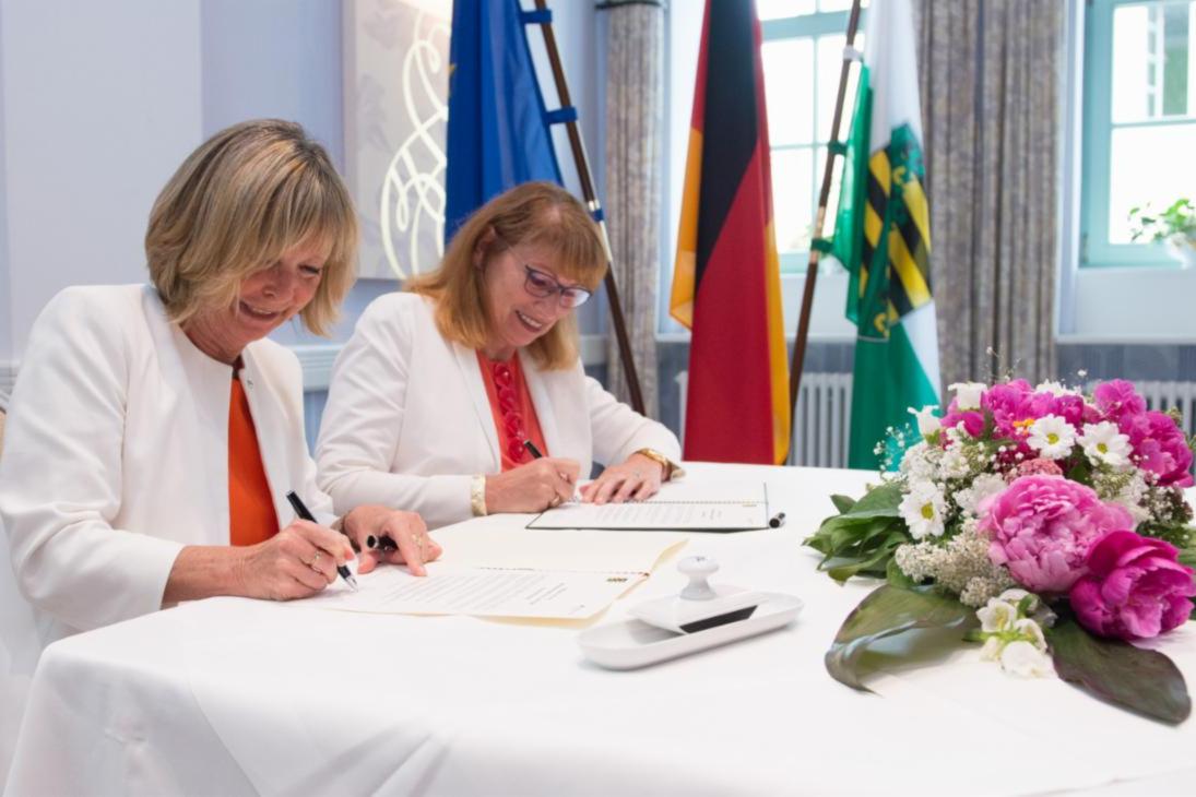 Christine Lüders, Leiterin der Antidiskriminierungsstelle des Bundes und Staatsministerin Petra Köpping unterzeichnen die Beitritts-Urkunde.