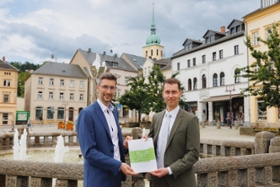 Foto: Der Präsident der Landesdirektion Sachsen, Béla Bélafi (rechts im Bild) übergibt dem Oberbürgermeister der Großen Kreisstadt Sebnitz, Ronald Kretzschmar, eine Bedarfszuweisung in Höhe von 1,4 Millionen Euro für die Ausrichtung des "Tag der Sachsen" 2025.