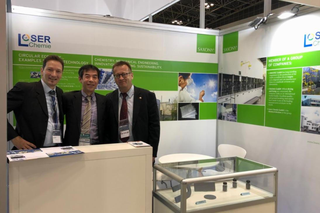 Dr. Palitzsch (l.) und Dr. Röver (r.) der Loser Chemie GmbH an ihrem Unternehmensstand auf der nano tech 2019 erhalten Besuch von Mr. Komoto (M.) vom japanischen Mizuho Information & Research Institute.