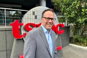 Foto: Wirtschaftsminister Dirk Panter steht vorm einem TSMC-Schriftzug vorm TSMC-Headquarter in Hsinchu