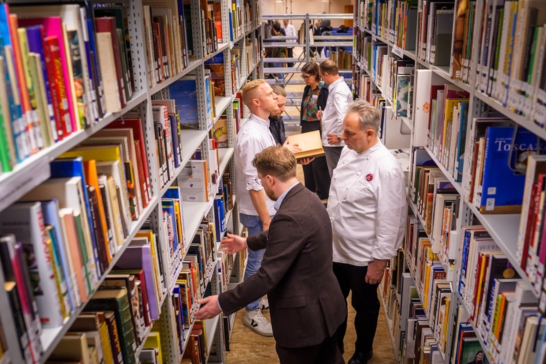 Besuch der Spitzenköche im Deutschen Archiv der Kulinarik: Erich Schwingshackl, Andreas Rieger, Christian Bau und Nils Henkel stöbern in den Regalen.