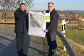 Foto: LDS-Präsident Béla Bélafi und der Dohnaer Bürgermeister Dr. Ralf Müller bei der Übergabe des Zuwendungsbescheides (v. l.). Im Hintergrund das fertiggestellte Hochwasserrückhaltebecken oberhalb des Ortsteils Krebs.