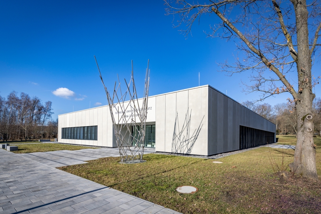 Das neu errichtete Transmissionselektronenmikroskopiezentrum der TU Chemnitz befindet sich am Universitätsstandort Erfenschlager Straße 73. Vor dem Eingang steht die 6,5 Meter hohe Plastik „Impact“ von Stefanie Welk, die Elemente aus der Elektronenmikroskopie und der Werkstoffforschung verbindet.
