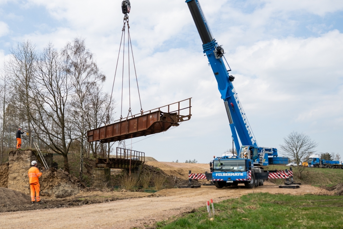 Ein Teil der alten Eisenbahnbrücke, die über den Holzbach führte, wird durch einen Kran ausgehoben.