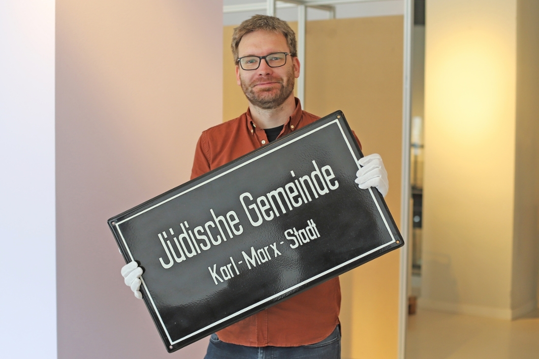 Kurator Dr. Alexander Walther mit der DDR-zeitlichen Emaille-Plakette der Jüdischen Gemeinde Chemnitz, damals Karl-Marx-Stadt.