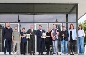 Foto: Landtagspräsident Alexander Dierks und Landesbeauftragter Michael Welsch mit Werkstatträten und Mitarbeitenden des Projekts "Mittendrin in Markkleeberg" auf der Freitreppe vor dem Plenargebäude des Sächsischen Landtags bei der Vorstellung der sächsischen Verfassung in Leichter Sprache